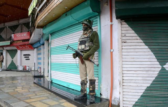A security personnel stands guard at a closed market during restrictions imposed to maintain law and order following a strike call by joint Hurriyat leadership against the killing of civilians during an encounter, in Srinagar on Friday. (PTI Photo)