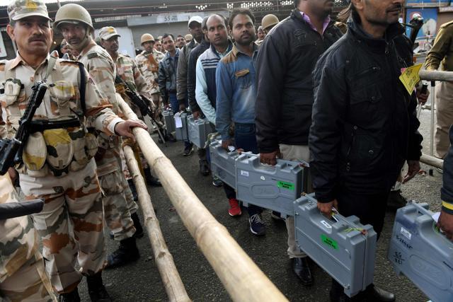 Workers on election duty carry Electronic Voting Machines (EVM) to a counting centre in Ghaziabad on March 11, 2017, under a heavy security detail. (AFP)
