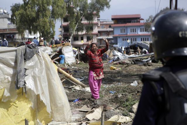 Nepalese woman ask to policeman to stop as they tore down temporary huts in an earthquake shelter in downtown Kathmandu, Nepal, onb March 14. (AP Photo)