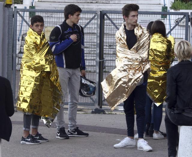 Schoolchildren, wrapped in blankets, wait nearby their high school in Grasse, southern France, after a 16-year-old student opened fire. (AP Photo)