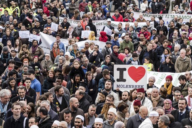 Marchers hold a banner which reads 'I love Molenbeek' as they walk to the Bourse during the one-year anniversary for Brussels attacks victims in Brussels on Wednesday, March 22, 2017. (AP Photo)