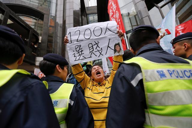 A woman shouts and holds a banner with the picture of candidate Carrie Lam as she joins others protesting during the election for Hong Kong's next chief executive in China on Sunday. (Reuters Photo)