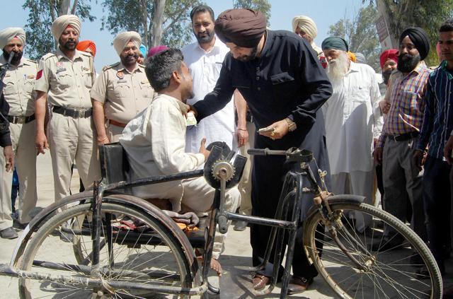 Sidhu giving money to a physically challenged man during his thanksgiving visit to Amritsar. (Sameer Sehgal/HT)