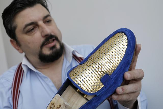 Antonio Vietri, artisan and founder of A&amp;V Fashion, shows a man shoe as part of his collection "Gold". (AFP Photo)