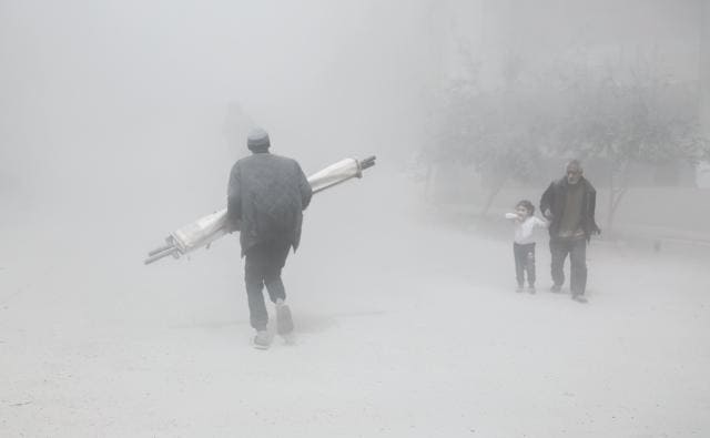 A Syrian man and girl flee past a man carrying a folded stretcher in Hamouria. (AFP Photo) A Syrian man and girl flee past a man carrying a folded stretcher in Hamouria. (AFP Photo)