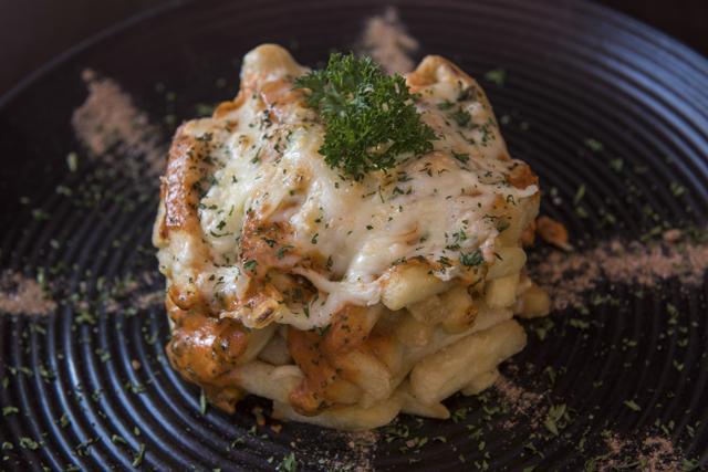 The Guntur chilli cheese fries come arranged in a neat column on a black spice-flecked plate. The combination of cheesiness, pungency and crispy fries makes it good enough to become a signature dish. (Aalok Soni/HT photo)