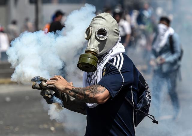 A Venezuelan opposition activists wears a gas mask during clashes with police in Caracas. (AFP) A Venezuelan opposition activists wears a gas mask during clashes with police in Caracas. (AFP)