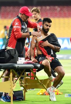 Royal Challengers Bangalore captain Virat Kohli gets bandage on his shoulder during a practice session at Chinnaswamy Stadium on Wednesday. Get live cricket score of Royal Challengers Bangalore vs Mumbai Indians here. (PTI) Royal Challengers Bangalore captain Virat Kohli gets bandage on his shoulder during a practice session at Chinnaswamy Stadium on Wednesday. Get live cricket score of Royal Challengers Bangalore vs Mumbai Indians here. (PTI)