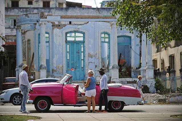 A tourist talks to locals next to an old American car in Havana. (Yamil Lage/AFP) A tourist talks to locals next to an old American car in Havana. (Yamil Lage/AFP)
