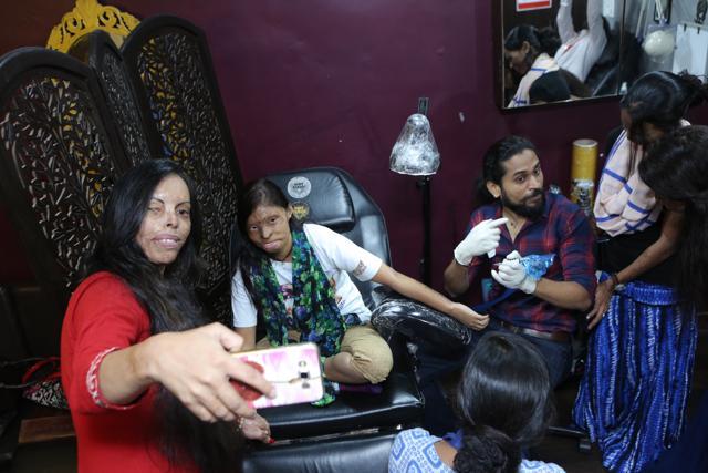 Acid attack survivors Soniya (L) and Rupa click a selfie as Laxmi discusses the intricacies of tattoo making with Vikas Malani. (Manoj Verma/HT Photo)