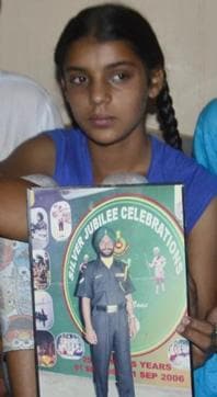 Khushdeep Kaur, 12, holding up the photo of her father, naib subedar Paramjit Singh at Vain Poin village of Tarn Taran district. (Sameer Sehgal/HT Photo)