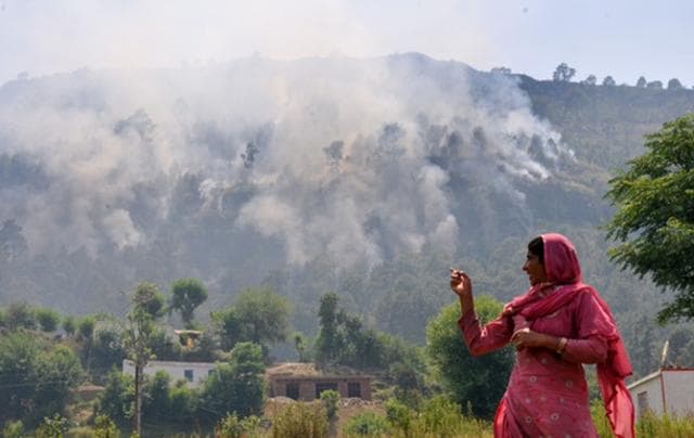 A lady points at smoke caused by firing of mortar shells from the Pakistan side of the border, at Jhangar village, in Nowshera. (Nitin Kantora/HT Photo)
