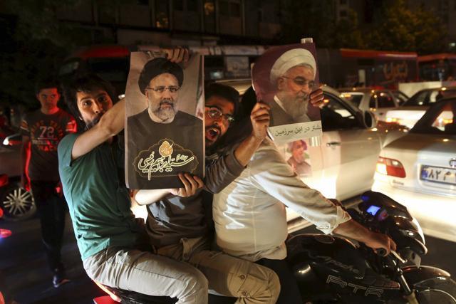 A supporter of Iranian President Hassan Rouhani, right, holds his poster as the other one holds a poster of his main rival Ebrahim Raisi during a street campaign. (AP Photo)