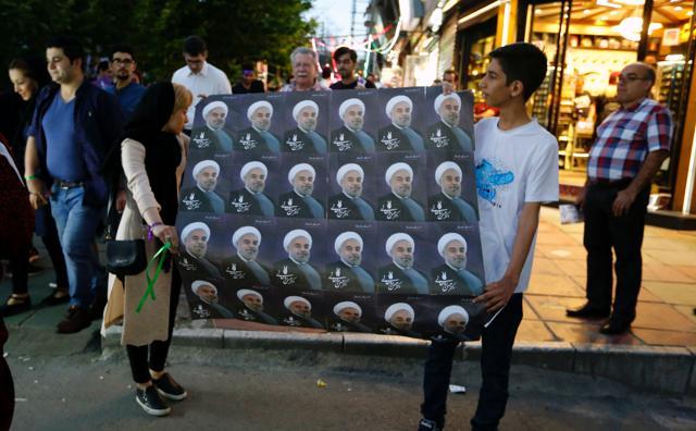 Supporters of Iranian President and election candidate Hassan Rouhani distribute brochures ahead of the Iranian presidential election in the streets of the capital Tehran on May 17, 2017. (AFP Photo)