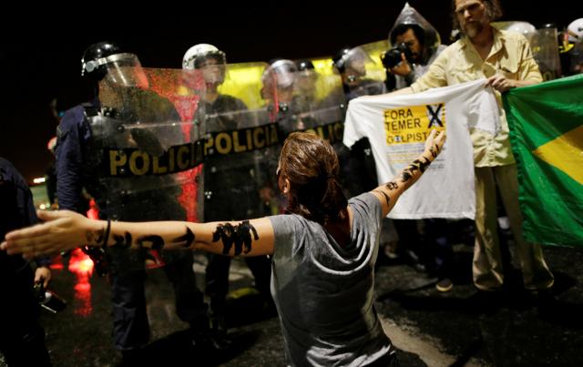 A demonstrator reacts near riot police officers during a protest against Brazil's President Michel Temer in Brasilia. (REUTERS) A demonstrator reacts near riot police officers during a protest against Brazil's President Michel Temer in Brasilia. (REUTERS)