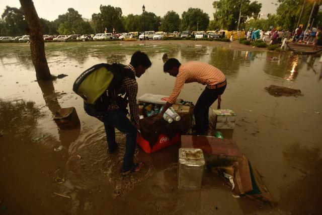 People near India Gate pack up their things as rainfall continues. (Burhaan Kinu/HT Photo)