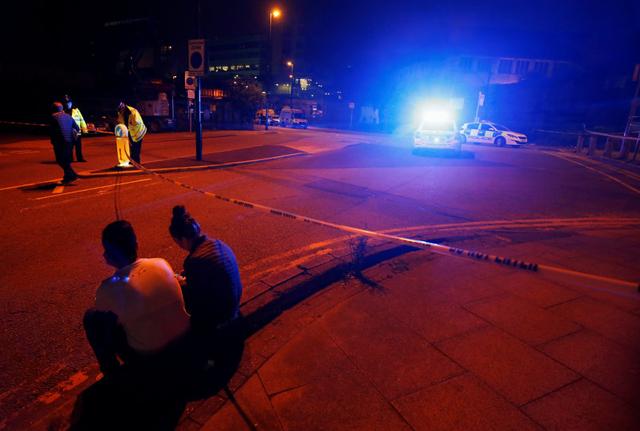 People sit by the side of the road next to a police cordon outside the Manchester Arena, where U.S. singer Ariana Grande had been performing, in Manchester, northern England, Britain, May 23. (REUTERS) People sit by the side of the road next to a police cordon outside the Manchester Arena, where U.S. singer Ariana Grande had been performing, in Manchester, northern England, Britain, May 23. (REUTERS)