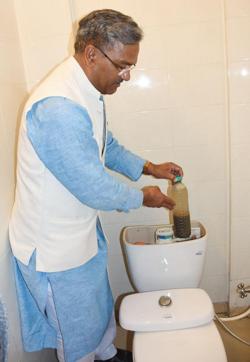 Chief Minister Trivendra Singh Rawat puts a sand-filled one-litre bottle in the flush of the toilet at his official residence. (HT Photo) Chief Minister Trivendra Singh Rawat puts a sand-filled one-litre bottle in the flush of the toilet at his official residence. (HT Photo)