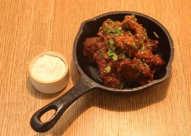 The ‘red hot’ chicken wings were crunchy enough, but more sweet than hot. The blue cheese dip alongside was barely cheesy, with none the bite of blue. (Bhushan Koyande / HT Photo)