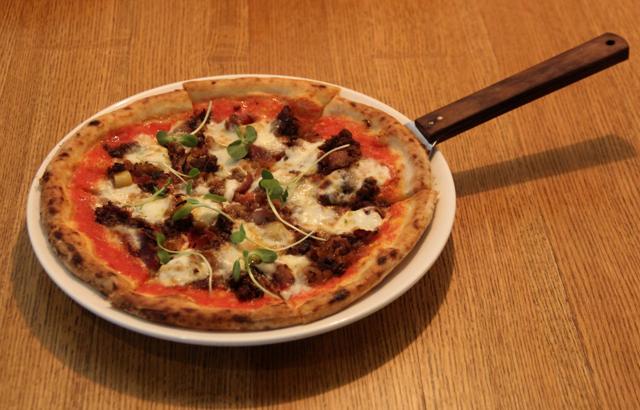 The thin-crust Old MacDonald pizza had choriz, bacon, potato cubes, pearl onions and pea shoots, so it was robust and smoky, but the meat was sinewy and dry, and the slightly charred crust otherwise doughy. (Bhushan Koyande / HT Photo )