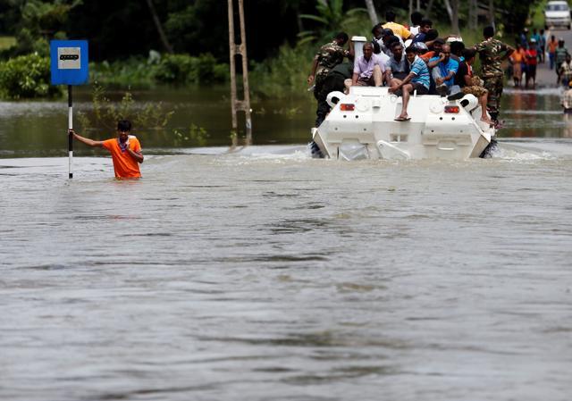 A man holds onto a bus stop post on a flooded road as people travel on top of an armoured personnel carrier on a flooded road in Bulathsinhala village in Kalutara. (Reuters Phoro) A man holds onto a bus stop post on a flooded road as people travel on top of an armoured personnel carrier on a flooded road in Bulathsinhala village in Kalutara. (Reuters Phoro)