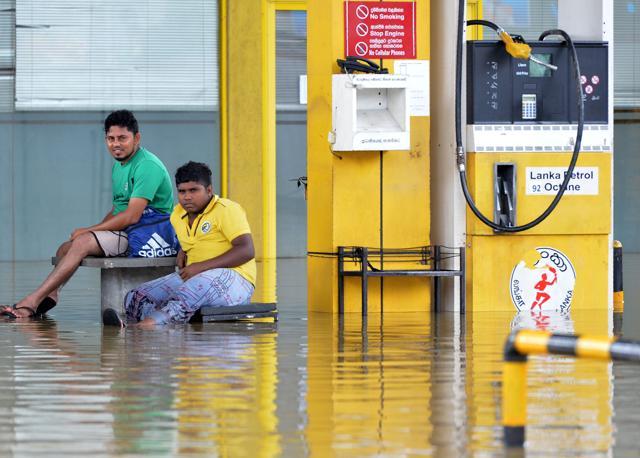 Sri Lankan gas station workers look over a flooded forecourt after rains in Kaduwela. (AFP Photo) Sri Lankan gas station workers look over a flooded forecourt after rains in Kaduwela. (AFP Photo)