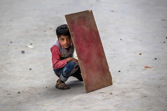 A boy hides behind a piece of plywood to shield himself from stones and glass marbles during a clash between protesters and security forces in Srinagar. (AP Photo) A boy hides behind a piece of plywood to shield himself from stones and glass marbles during a clash between protesters and security forces in Srinagar. (AP Photo)