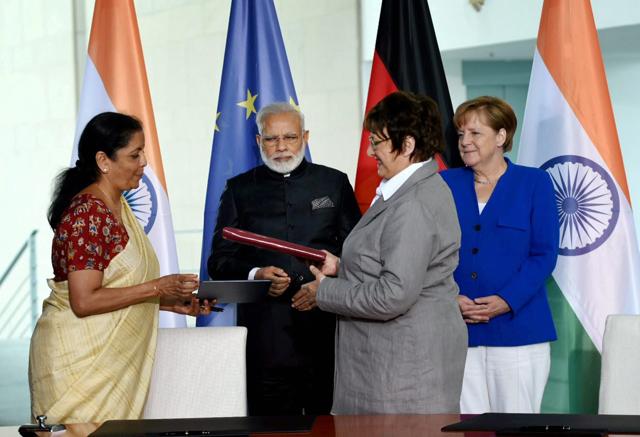 Prime Minister Narendra Modi and German Chancellor Angela Merkel look on as MoUs are exchanged between commerce minister Nirmala Sitharaman and a German representative in Berlin on Tuesday. (PTI/ PIB Photo) Prime Minister Narendra Modi and German Chancellor Angela Merkel look on as MoUs are exchanged between commerce minister Nirmala Sitharaman and a German representative in Berlin on Tuesday. (PTI/ PIB Photo)