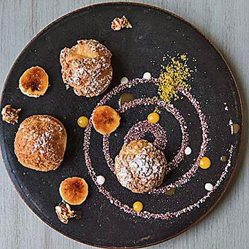 Keep room for dessert. The Paris Brest, light puffs of choux pastry with caramelised bananas, chopped nuts and broken bits of meringue, is a fine way to end the meal. (Aalok Soni / HT Photo)