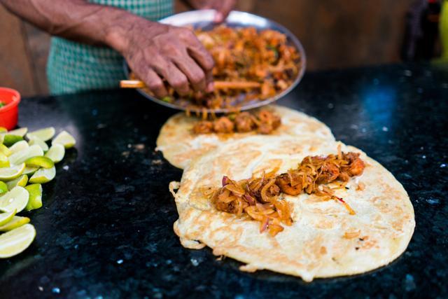 Two chicken and egg kathi rolls with onions being prepared by a street food vendor. (Shutterstock) Two chicken and egg kathi rolls with onions being prepared by a street food vendor. (Shutterstock)