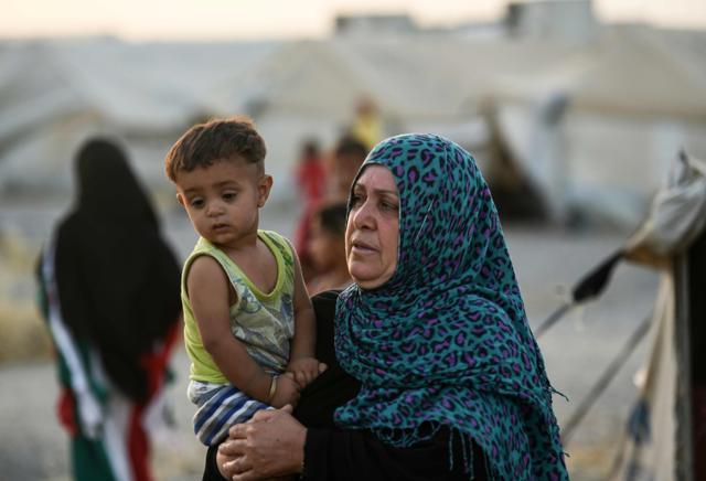A displaced Iraqi woman carries a child at the Hasan Sham camp for internally displaced people on June 10, 2017. (AFP Photo) A displaced Iraqi woman carries a child at the Hasan Sham camp for internally displaced people on June 10, 2017. (AFP Photo)