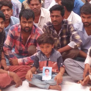 Rudra Singh sits with a photo of his deceased father who was killed in police firing. (HT PHOTO)
