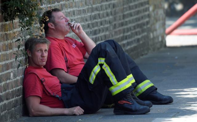 Firefighters rest near a tower block, severely damaged in a serious fire, in north Kensington. (Reuters Photo) Firefighters rest near a tower block, severely damaged in a serious fire, in north Kensington. (Reuters Photo)