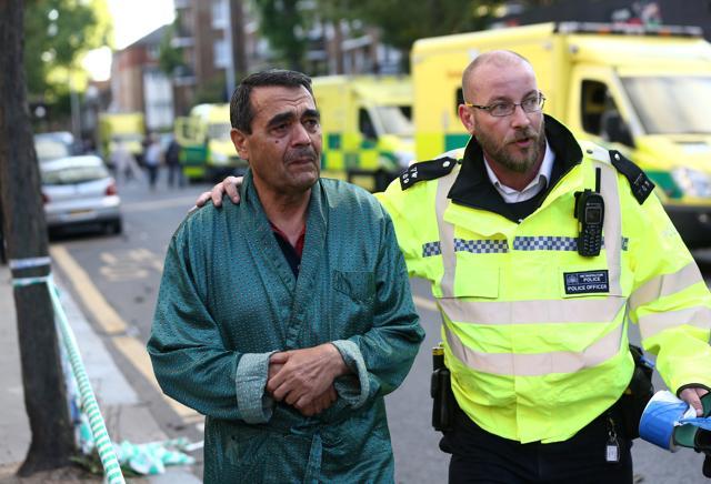 A police officer helps evacuate a resident from near the raging tower block at Latimer Road in West London. (Reuters Photo) A police officer helps evacuate a resident from near the raging tower block at Latimer Road in West London. (Reuters Photo)