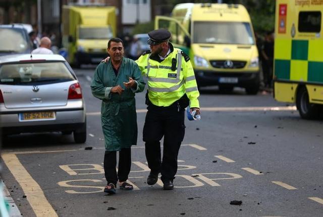 A police officer helps to evacuate a local resident from close to the scene of a serious fire in a tower block at Latimer Road in West London. (Reuters Photo) A police officer helps to evacuate a local resident from close to the scene of a serious fire in a tower block at Latimer Road in West London. (Reuters Photo)