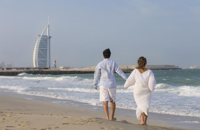 A couple walking on the beach in Dubai with Burj Al Arab in the background. (Shutterstock) A couple walking on the beach in Dubai with Burj Al Arab in the background. (Shutterstock)