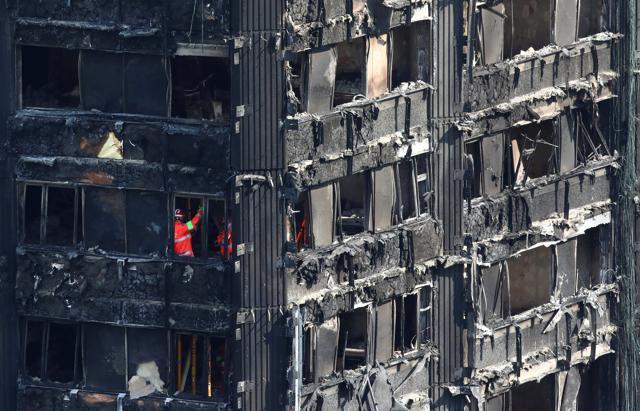 Members of emergency services work inside the burnt out remains of the Grenfell Tower in North Kensington, London, on June 18, 2017. (Reuters)