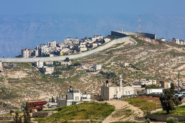 A small village and Palestinian town on the hill behind the separation wall on the West Bank in Israel. (Shutterstock)