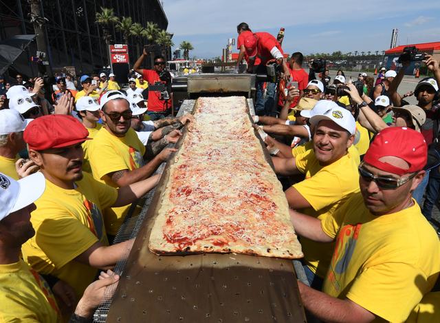 Volunteers feed the final section of the pizza into the mobile oven as they successfully break the Guinness World Record for longest pizza in Fontana, California. (AFP) Volunteers feed the final section of the pizza into the mobile oven as they successfully break the Guinness World Record for longest pizza in Fontana, California. (AFP)