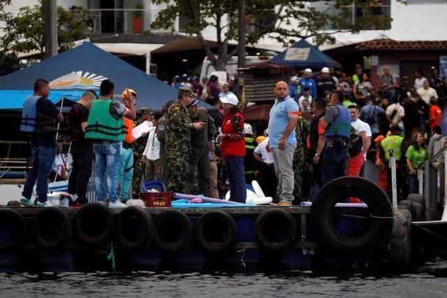 Rescuers wait at the dock after a tourist boat sank in the Guatape reservoir (Reuters ) Rescuers wait at the dock after a tourist boat sank in the Guatape reservoir (Reuters )