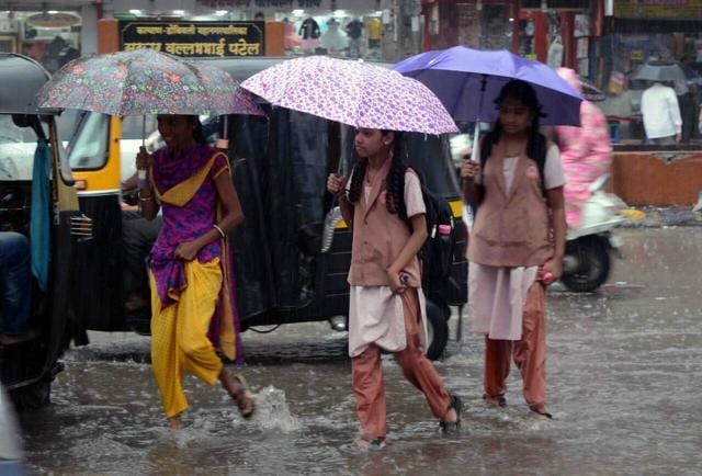 Young girls walk on a waterlogged road to get to school in Kalyan. (Rishikesh Choudhary/Hindustan Times)