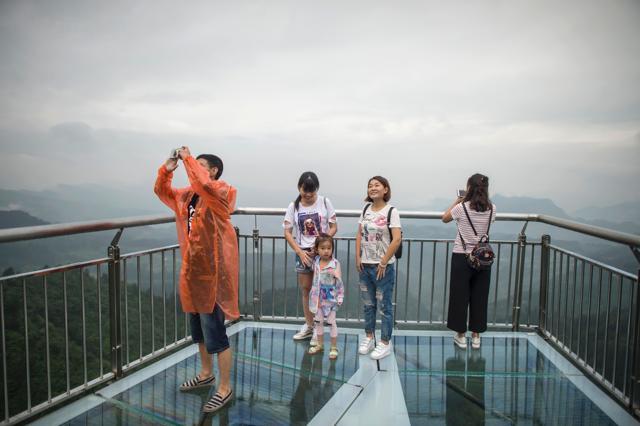 Tourists look on from the skywalk and take photos. (AFP/Fred Dufour)