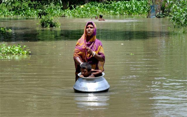 A woman with her child, in a utensil, moves to a safer place from the flood affected Khanamukh village in Morigoan, Assam on July 5, 2017. (PTI) A woman with her child, in a utensil, moves to a safer place from the flood affected Khanamukh village in Morigoan, Assam on July 5, 2017. (PTI)