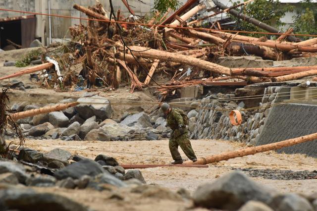 A defence forces personnel crosses a river during rescue operations in Asakura. (AFP Photo) A defence forces personnel crosses a river during rescue operations in Asakura. (AFP Photo)