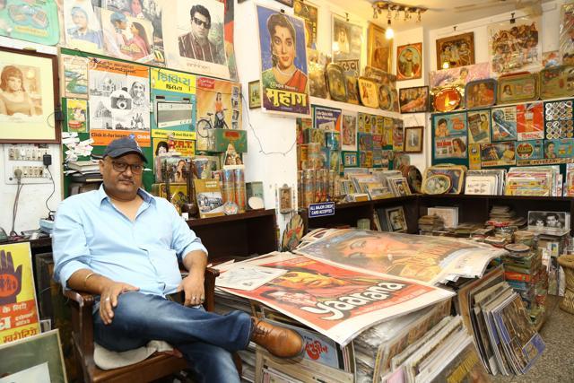 Owner, Deepak Jain, poses next to the vintage hand-painted posters of Bollywood blockbusters. (Raajessh Kashyap/HT)