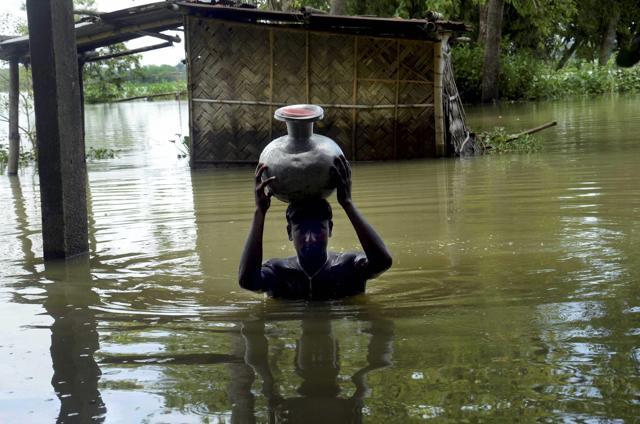 A boy carries fresh drinking water on head as he wades through flooded water at Padder parr village in Karimganj district, Assam. (PTI Photo) A boy carries fresh drinking water on head as he wades through flooded water at Padder parr village in Karimganj district, Assam. (PTI Photo)