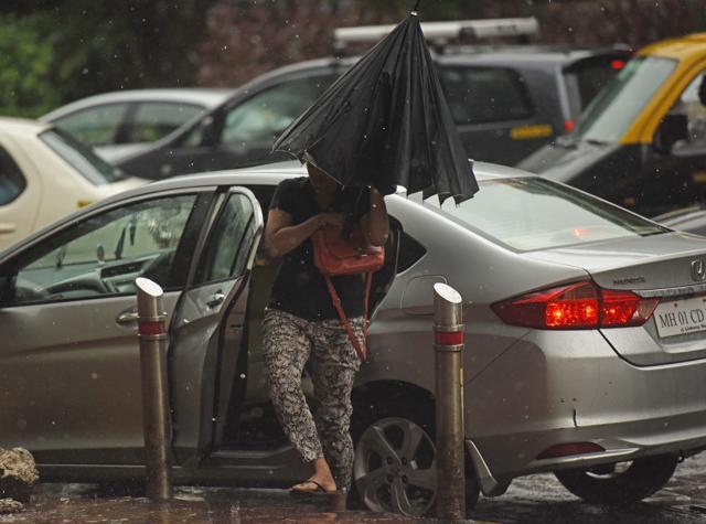 A woman cautiously gets out of her car at Dadar owing to the downpour. (Satyabrata Tripathy/HT Photo)