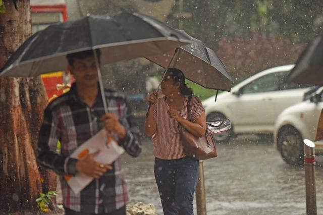 Pedestrians shield their documents and other valuables from the rain at Dadar. (Satyabrata Tripathy/HT Photo)