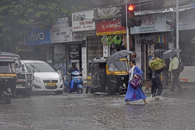 A pedestrian looks disgusted as she makes her way across a flooded street in Kurla. (Pratik Chorge/HT Photo)