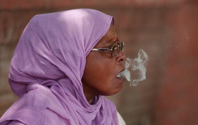 A woman smokes a beedi or local cigarette hand-rolled with tobacco leaf on a roadside in New Delhi. (Reuters Photo) A woman smokes a beedi or local cigarette hand-rolled with tobacco leaf on a roadside in New Delhi. (Reuters Photo)